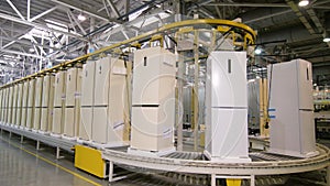 Row of domestic fridges transported by conveyor at plant