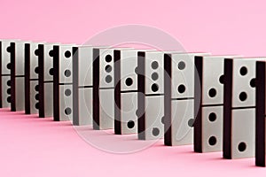 Row of domino tiles on pink studio background close up