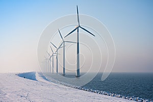 Row of Dutch windmills disappearing in winter haze