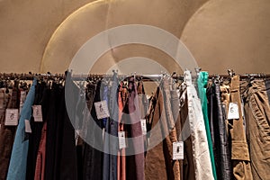 Row of earth tone colour fabric jeans or denim trousers and slacks hang on hanger. photo
