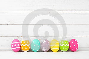 Row of Easter eggs over a rustic white wood background