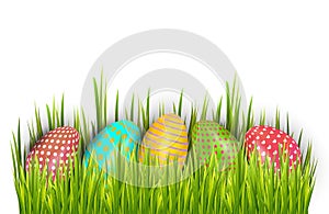 Row of Easter painted eggs hidden in green grass and isolated on white background.