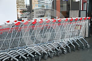 Row of empty metal shopping carts near supermarket outdoors