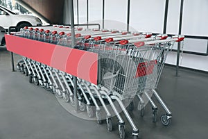 Row of empty metal shopping carts near supermarket outdoors