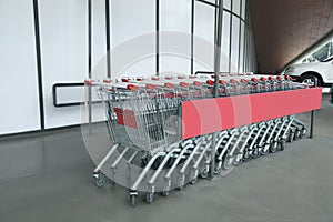 Row of empty metal shopping carts near supermarket outdoors