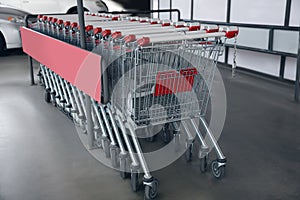 Row of empty metal shopping carts near supermarket outdoors