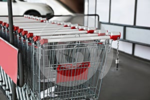 Row of empty metal shopping carts near supermarket outdoors