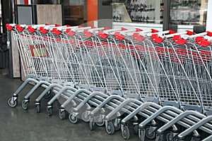 Row of empty metal shopping carts near supermarket outdoors