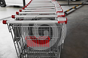 Row of empty metal shopping carts near supermarket outdoors