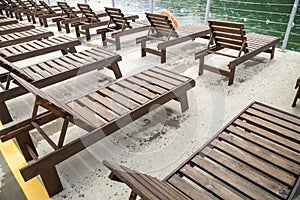 Row of empty wooden beach chairs near water