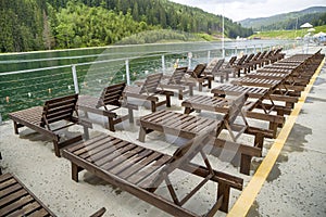 Row of empty wooden beach chairs near water