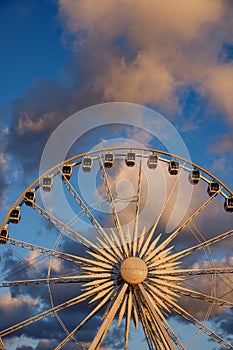 The row of Ferris wheel cabins against the backdrop of beautiful sunset red clouds.