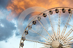 The row of Ferris wheel cabins against the backdrop of beautiful sunset red clouds.