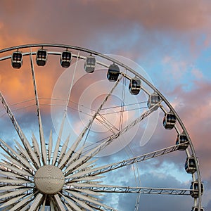 The row of Ferris wheel cabins against the backdrop of beautiful sunset red clouds.