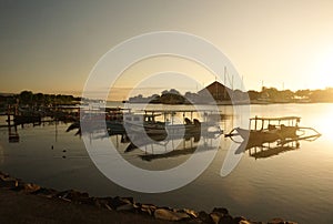 A row of fishing boats leaning against the pier with a beautiful sunrise.