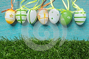 A row of five colorful easter eggs on blue Background and grass