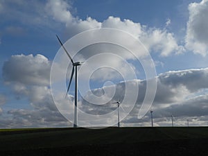 Row of five wind turbines surrounded by cottony clouds
