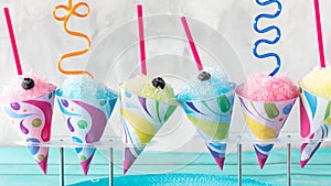 A row of flavoured snow cones with silly straws against a light background. photo