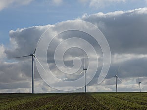 Row of four wind turbines surrounded by cottony clouds