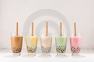 Row of fresh boba bubble tea glasses with straw on white background