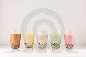 Row of fresh boba bubble tea glasses on white background