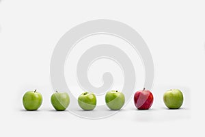 Row of fresh green apples with a single red one