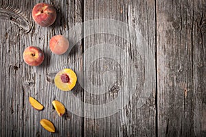 A row of freshly picked whole and sliced peaches on a wooden background.