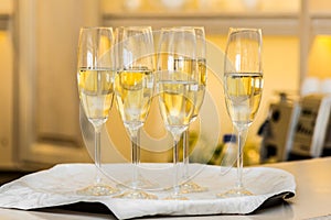 A row of glasses filled with champagne are lined up ready to be served
