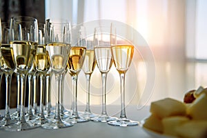 A row of glasses filled with cold champagne lined up, ready to be served. Glasses with Martini on the table - party background