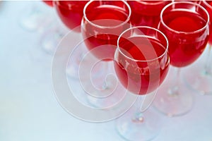 A row of glasses with red drinks, juice, champagne or wine at a party. Catering. Glassware on the table with a white tablecloth.