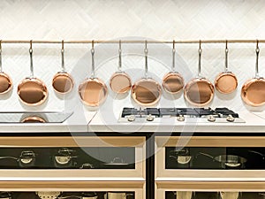 Row of gleaming copper pans hanging on the wall