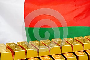 Row of gold bars on the Madagascar flag background. Concept of gold reserve and gold fund of Madagascar