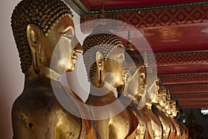 Row of golden buddha statues in temple cloisters