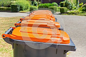 Row of gray garbage containers along the street