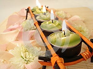 Row of green candles over straw matt with rose petals photo