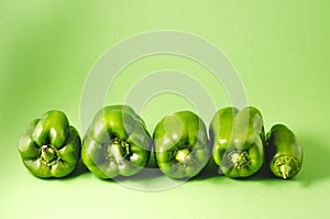 Row green paprika pepper isolated on a green background/Row of fresh green paprika pepper on green background