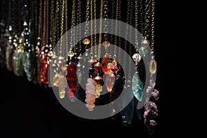a row of hanging necklaces on a black background