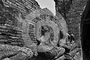 Row of headless Buddha images beside broken brick wall