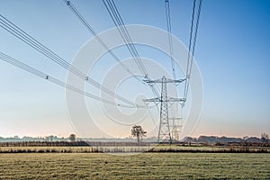 Row of high-voltage pylons with cables in a wintry landscape