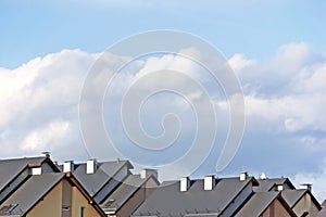 Row house roofs, condo rooftop panorama and bright summer clouds, panoramic roofscape sunny summer cloudscape