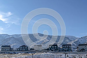 Row of houses against snow dusted hills and blue sky on a gloomy winter day