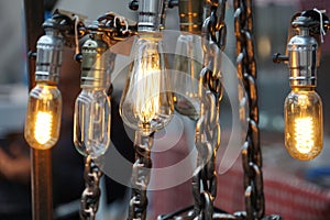Row of industrial retro light bulbs on silver chains at a market stand in Greenwich London