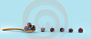 a row of juicy summer cherry on a wooden spoon on a pure blue background