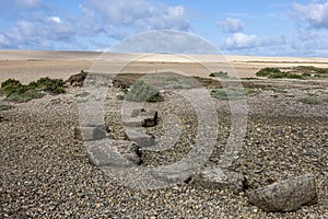 A row of large rocks leading up to Chesil beach on early morning walk to Portland, Dorset, on a beautiful sunny summer day .