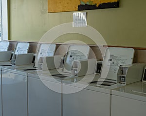 Row of laundry coin operated laundry machines inside a laundromat