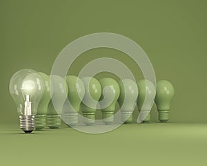 Row of light bulbs with glowing one different idea on green background