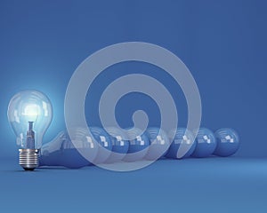 Row of light bulbs with glowing one different idea from the others on blue background