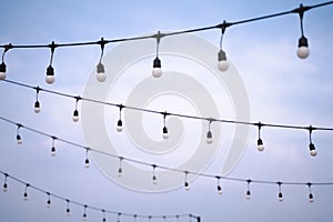 A row of light bulbs hanging on a wire on a bright sky background