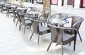 Row of little tables with chairs in open cafe