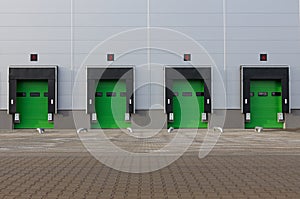 Row of loading docks with shutter doors at warehouse. Green gate, front view
